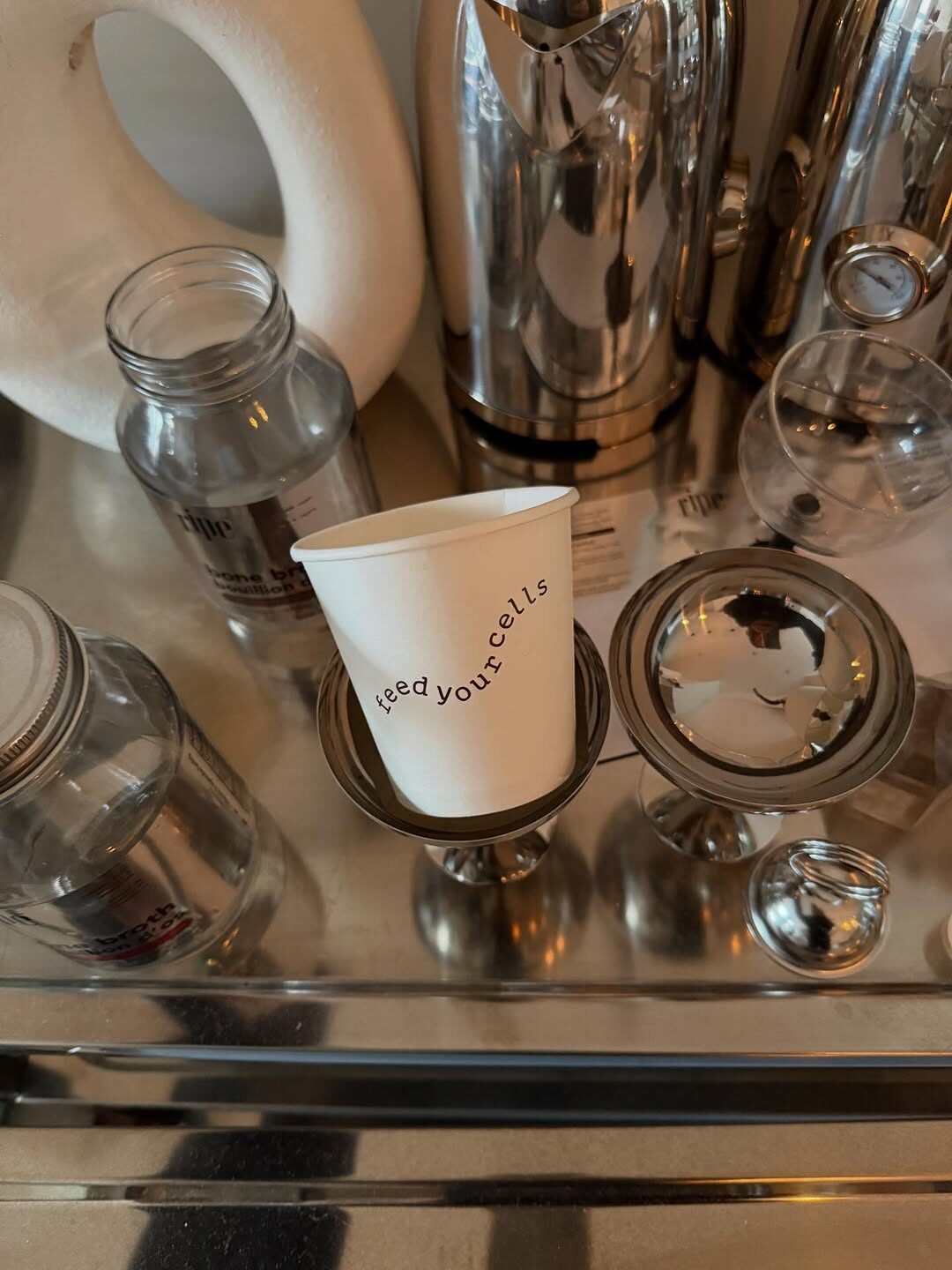 Lisbon pop-up still life with feed your cells paper cup, glass jars, and stainless serveware
