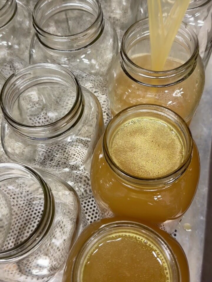 Golden bone broth pouring into mason jars in the morning