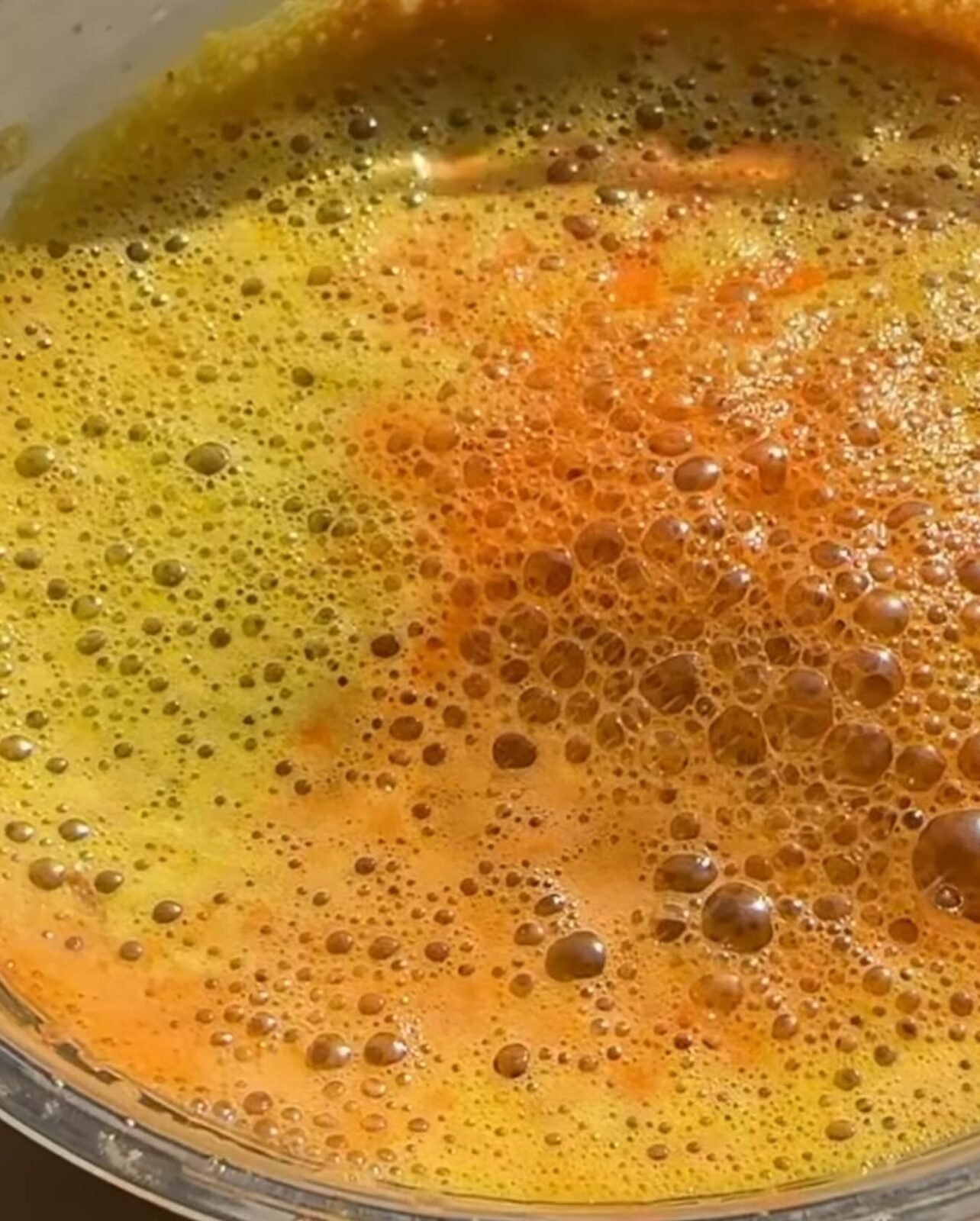 Swirling golden turmeric bone broth with bubbles