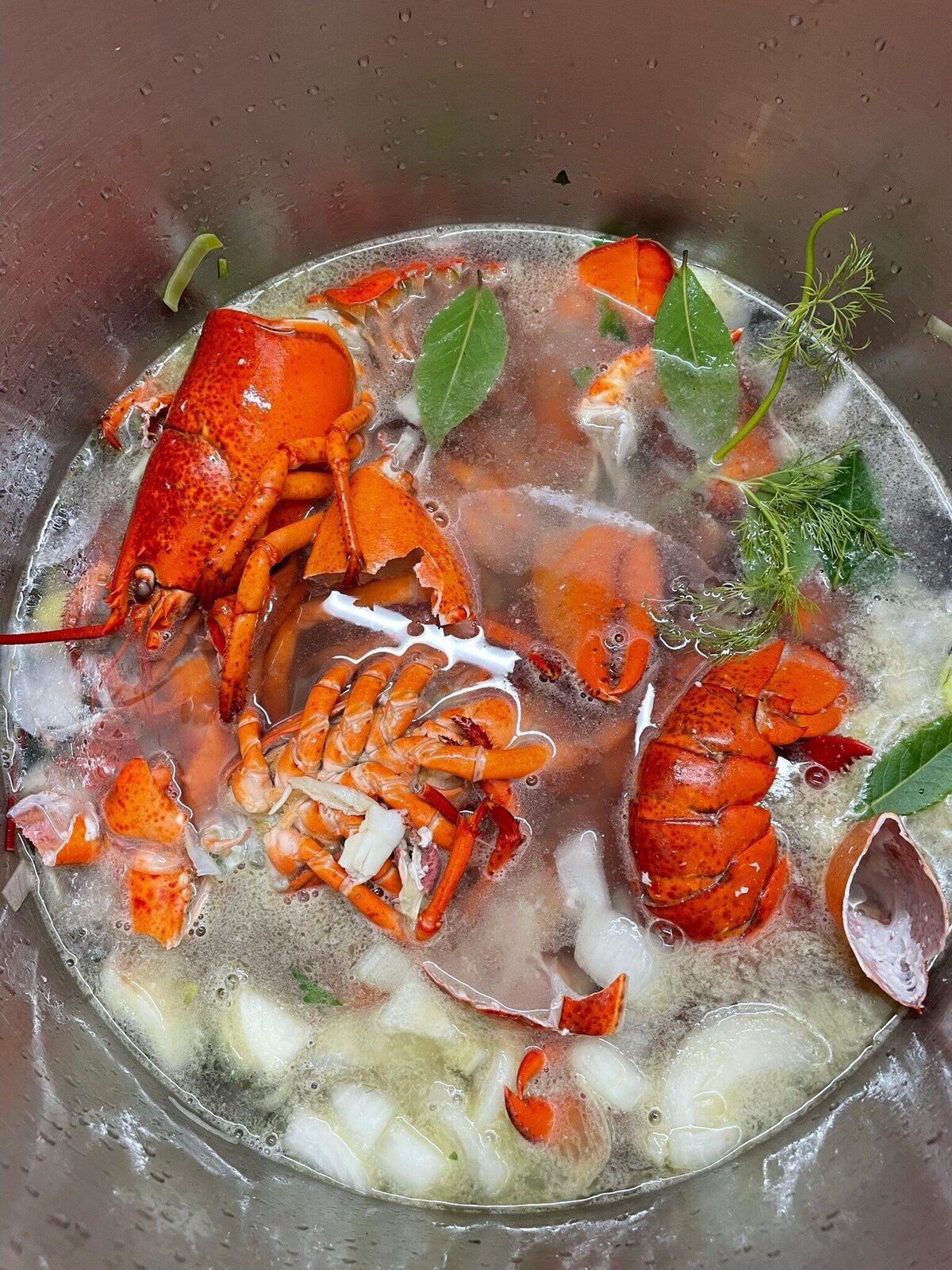 A large pot of seafood soup with crab legs, prawns and herbs
