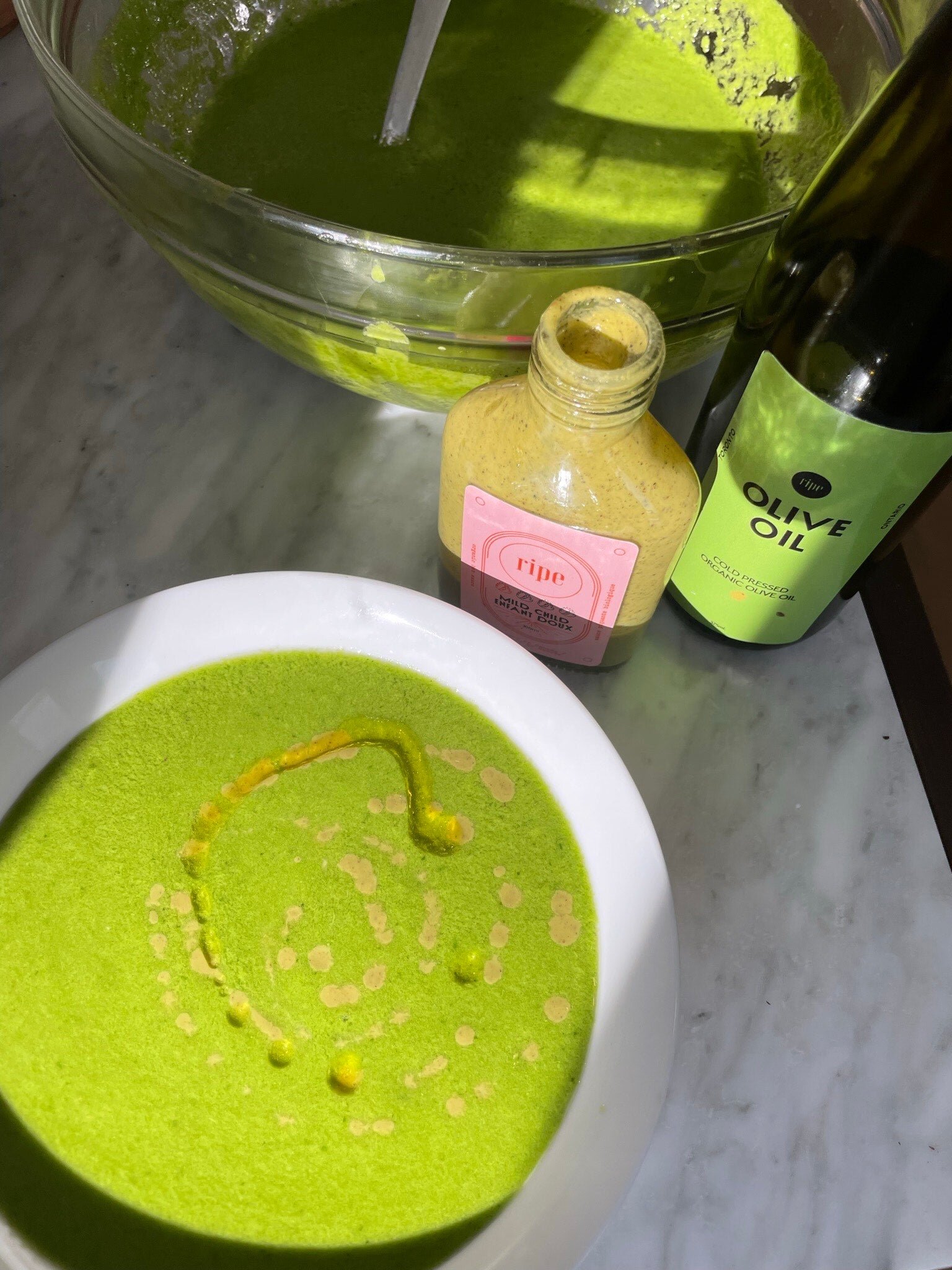 A bowl of bright green pureed soup with herbs scattered on top