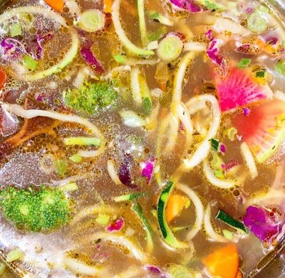 Rainbow noodles bowl with ginger-lemon bone broth, vegetables and herbs